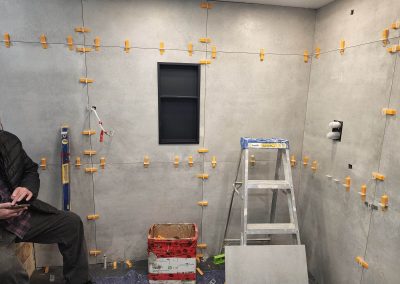 Installation céramique 30 x 30 imitation ciment au mur dans une douche à l’italienne
